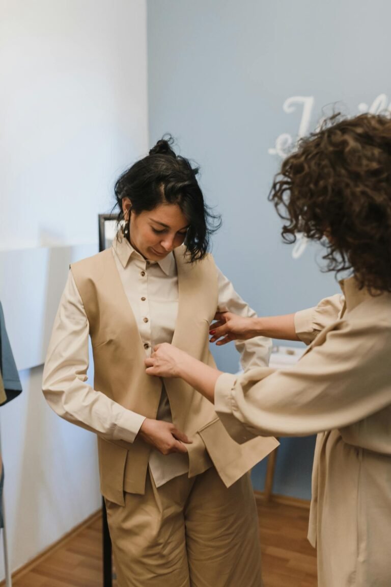 A boutique tailor adjusting a vest for a young customer inside a shop.
