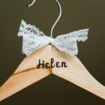 Close-up of a personalized wooden hanger with lace bow embellishment, perfect for bridal or fashion settings.