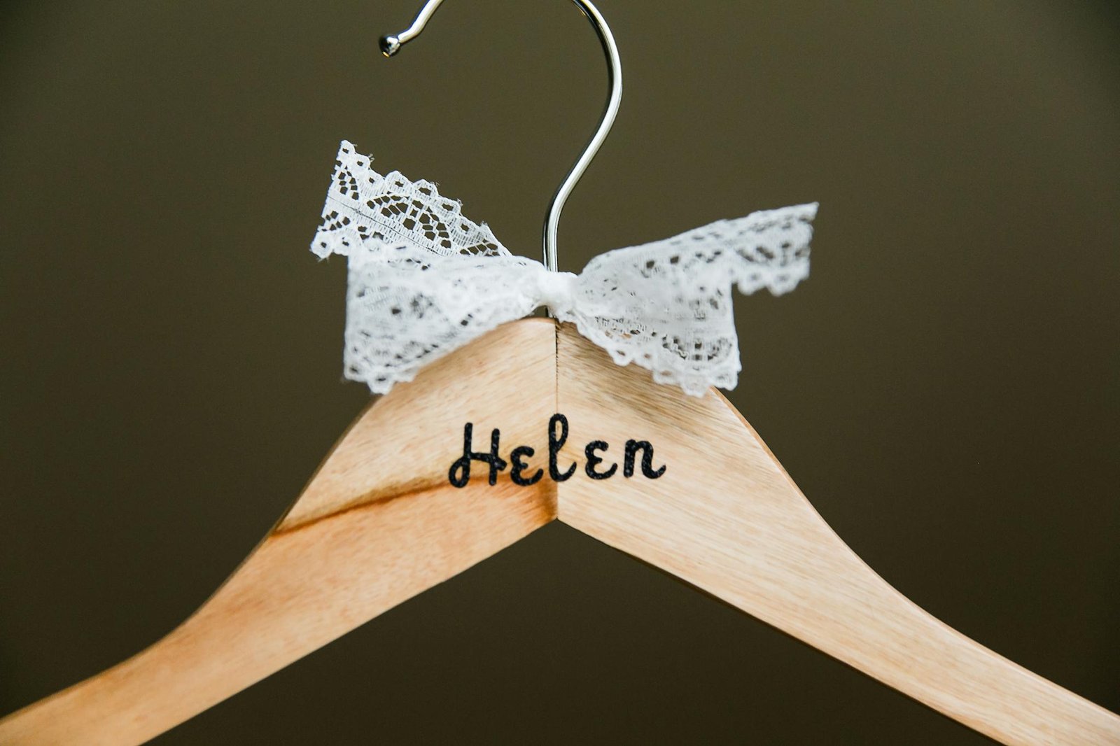 Close-up of a personalized wooden hanger with lace bow embellishment, perfect for bridal or fashion settings.