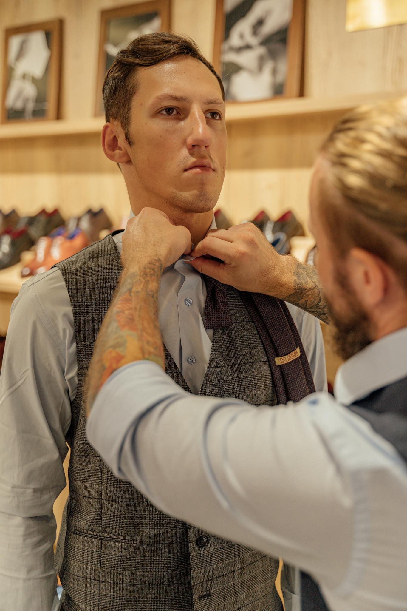 Tailor adjusting a client's vest and shirt in a clothing store, showcasing craftsmanship.