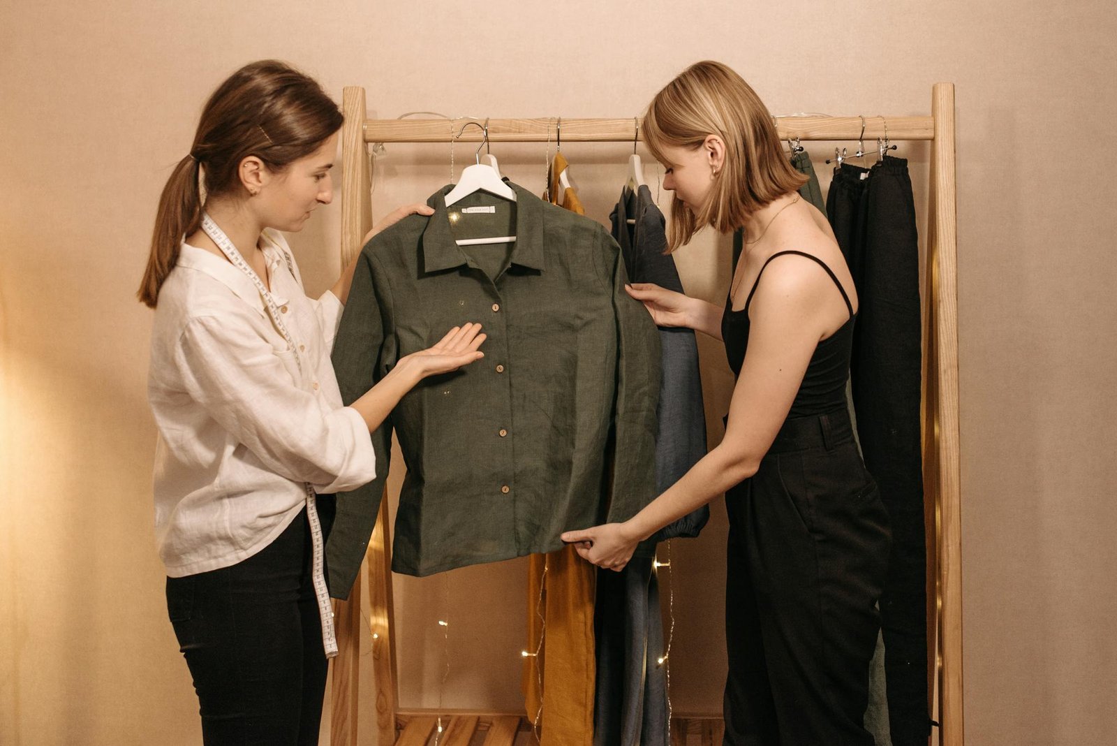 Two women discussing a green shirt in a professional tailor's workspace.